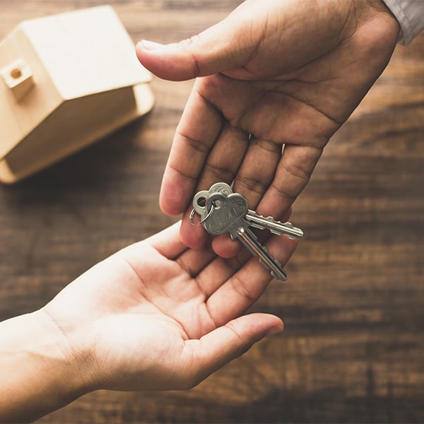 one person handing off key to another person